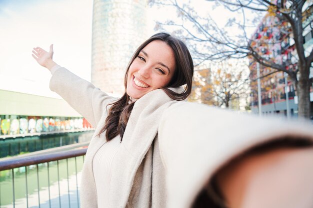 Retrato de Selfie de una joven muy sonriente de pie al aire libre en un parque una chica feliz divirtiéndose