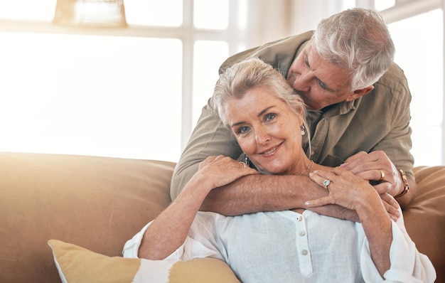 Foto retrato sênior e um casal se beijam e se abraçam no sofá da sala para cuidar do amor e se relacionar casa feliz e um homem e uma mulher idosos com romance juntos por gratidão aposentadoria e bondade