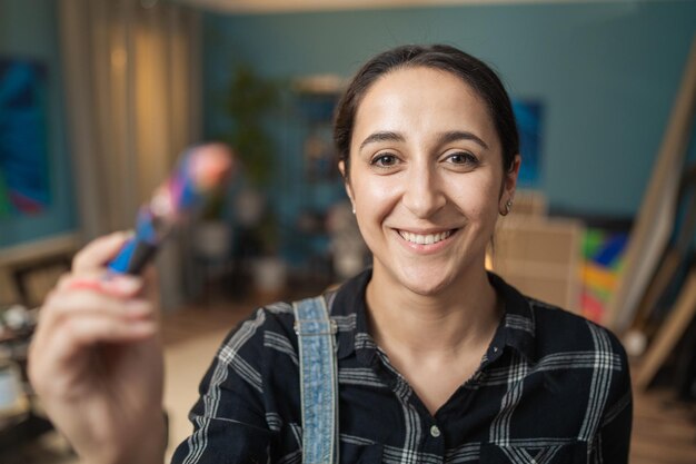 Retrato de una señora feliz sonriente que estira su mano en la que sostiene un cepillo sucio con aceite p