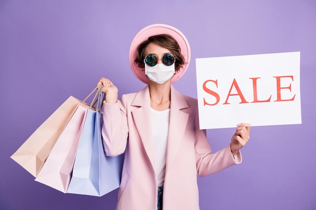 Retrato de señorita mantenga compras venta banner use gafas máscara segura contra la gripe capa rosa aislado sobre fondo púrpura
