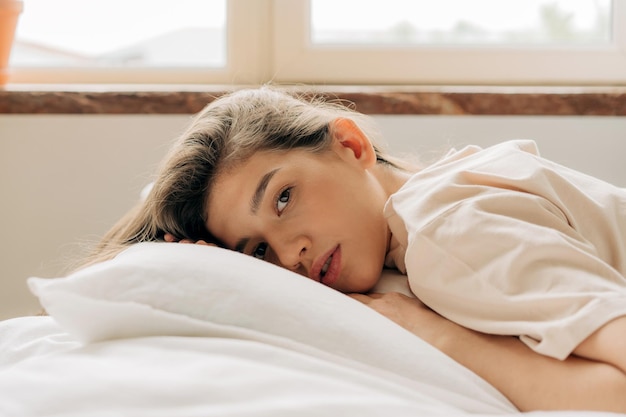 Retrato de una sensual y hermosa mujer joven tendida en la cama