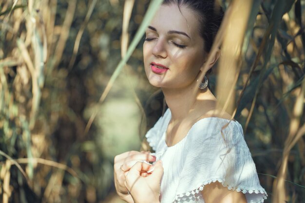 Retrato sensual sexy de una chica modelo con vestido blanco en el fondo de las cañas