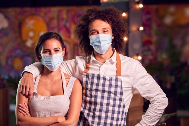 Foto retrato de servidores masculinos y femeninos que trabajan en el turno nocturno en el bar restaurante o club con máscaras faciales