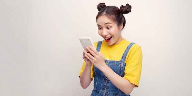 Retrato si una joven sorprendida vestida mirando un teléfono móvil aislado sobre fondo blanco