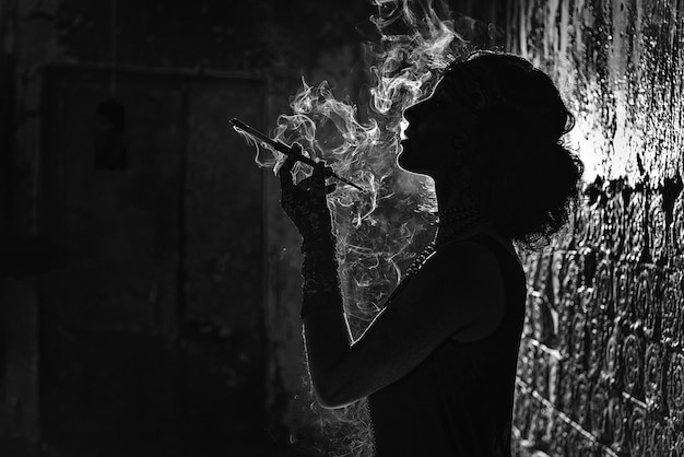 Un retrato de silueta en blanco y negro de una mujer joven fumando un cigarrillo en una boquilla.