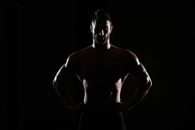 Retrato de silueta de un hombre joven en buena forma física que muestra su cuerpo bien entrenado Muscular culturista atlético modelo de fitness posando después de los ejercicios