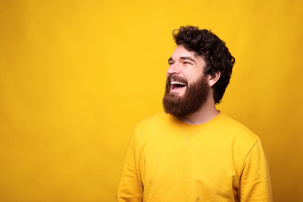 Retrato simples de um homem alegre com um grande sorriso no fundo amarelo.