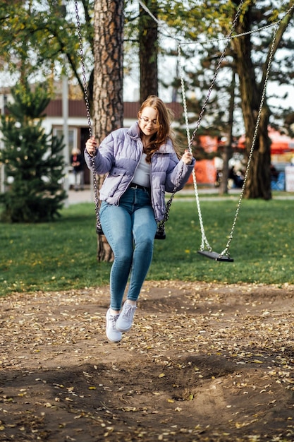 Retrato sincero de una hermosa joven en un columpio en el día de la primavera al aire libre feliz estudiante adolescente