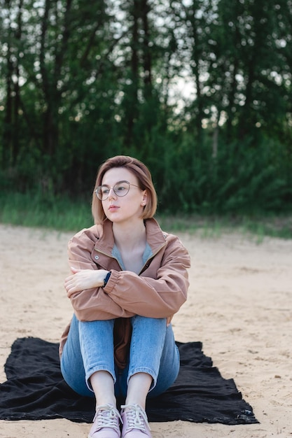 Foto retrato sincero de una joven caucásica de cabello corto sentada en la arena de la playa