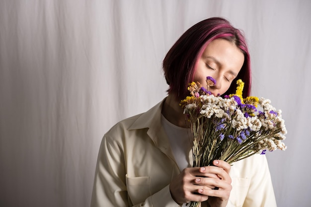 Retrato sincero de una joven hermosa mujer pacífica con cabello morado con un ramo