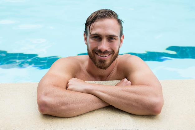 Retrato de socorrista sonriente apoyado en la piscina