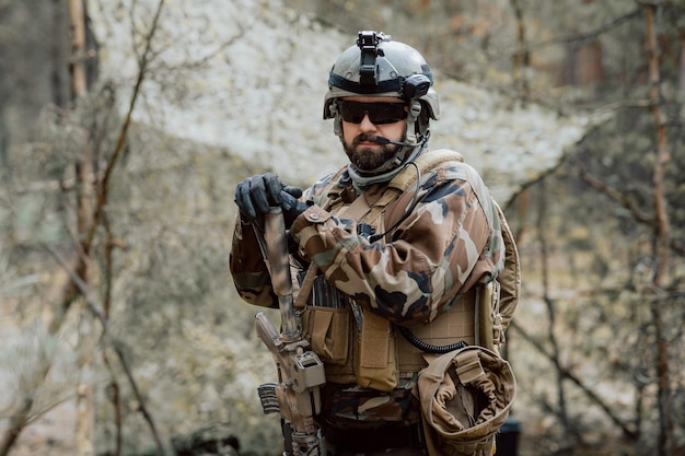 Retrato de un soldado barbudo de mediana edad con uniforme militar del bosque y casco con auriculares