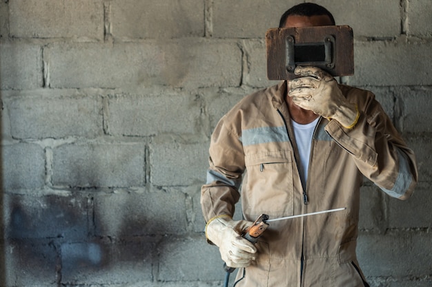Retrato de un soldador que cubre su rostro con una mascarilla en un taller