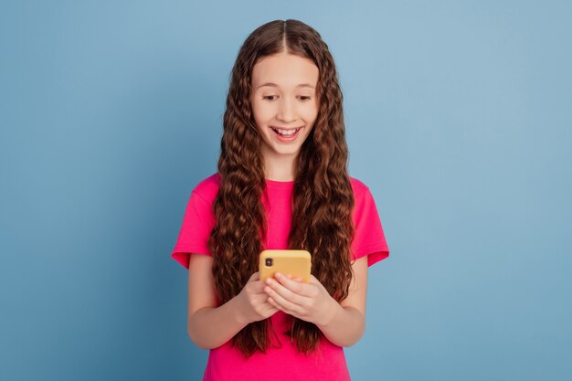 Retrato de soñadora graciosa señorita mantenga celular reacción de asombro sobre fondo azul.