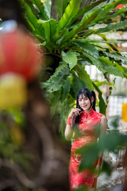 Retrato sonríe mujer transgénero asiática con vestido rojo cheongsam decoración tradicional para el festival de año nuevo chino celebrar la cultura de China en el santuario chino Lugares públicos en Tailandia