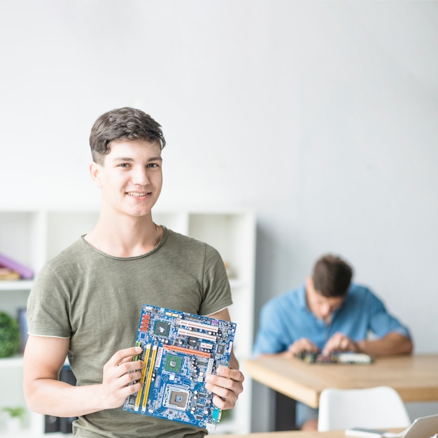 Foto retrato de sonriente adolescente sosteniendo la placa base