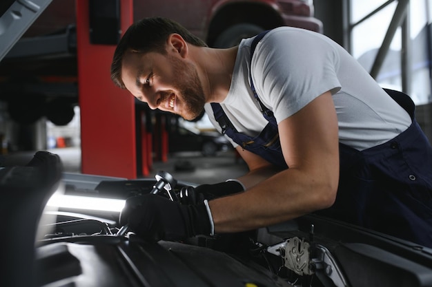 Retrato de un sonriente arreglando un motor de automóvil en su garaje