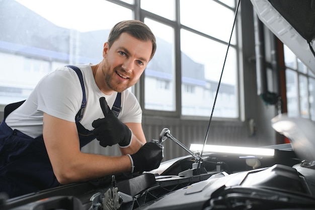 Retrato de un sonriente arreglando un motor de automóvil en su garaje
