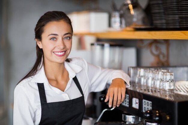 Retrato de sonriente camarera haciendo una taza de café