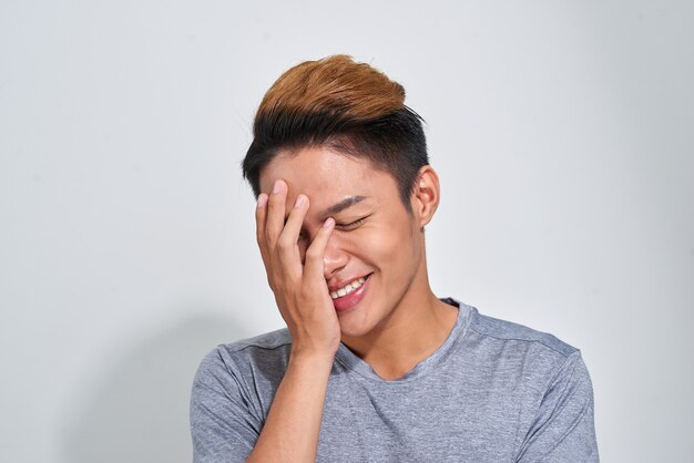 Retrato de sonriente deporte feliz hombre vestido con camiseta sobre fondo gris studio