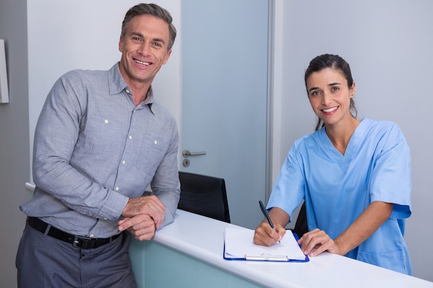 Retrato, de, sonriente, doctor, tenencia, pluma, posición, por, hombre, en el escritorio