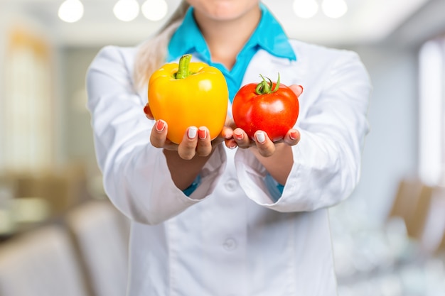 Foto retrato de sonriente doctora en bata blanca con verduras frescas aisladas