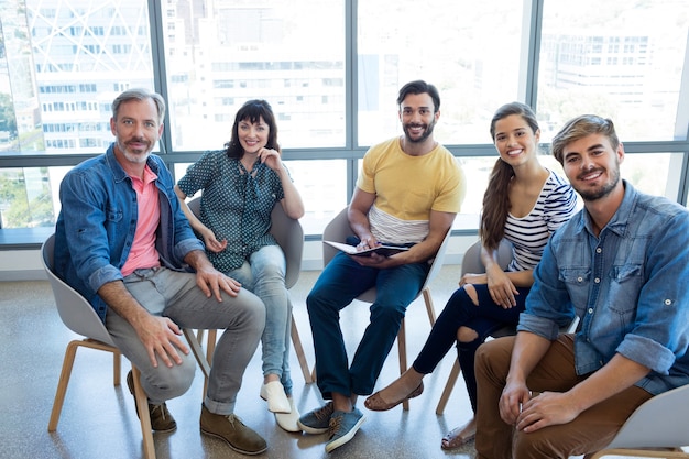 Retrato de sonriente equipo de negocios creativos sentados juntos en la oficina