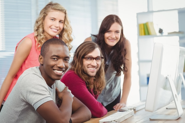 Retrato de sonriente equipo de negocios trabajando en el escritorio de la computadora