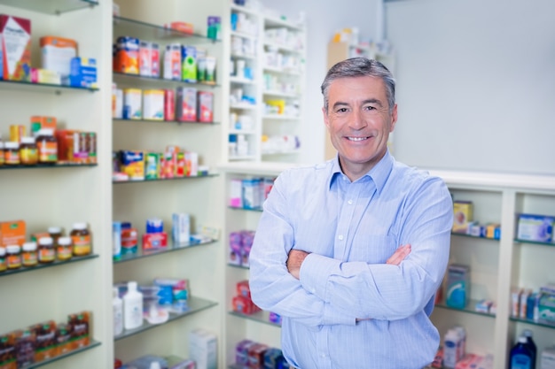 Retrato de un sonriente farmacéutico de pie con los brazos cruzados