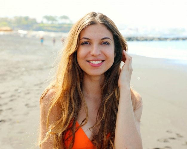 Retrato de sonriente hermosa chica sensual en bikini naranja en la playa
