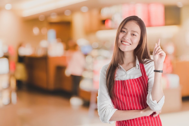 Retrato de sonriente hermosa mujer asiática joven usar delantal rojo