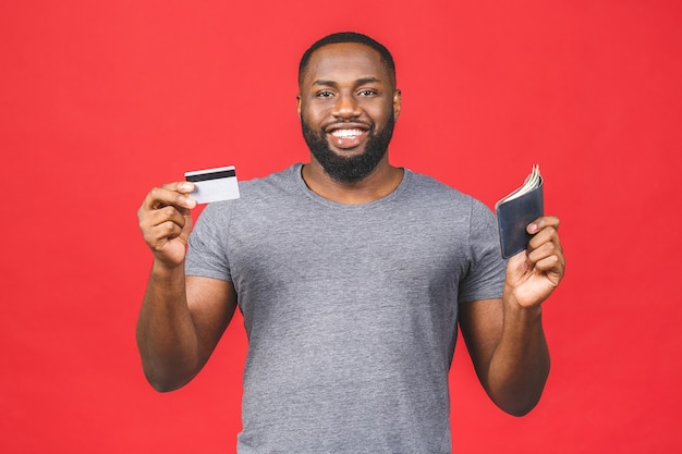 Retrato de un sonriente hombre barbudo negro afroamericano mostrando tarjeta de crédito y billetera con dinero