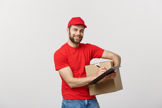 Retrato de sonriente hombre repartidor escribiendo en portapapeles y caja de retención.