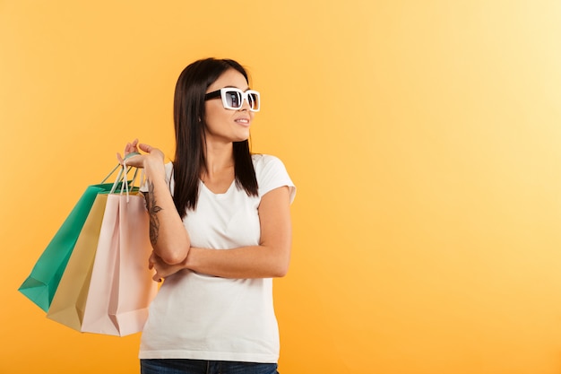 Retrato de una sonriente joven asiática con bolsas de compras