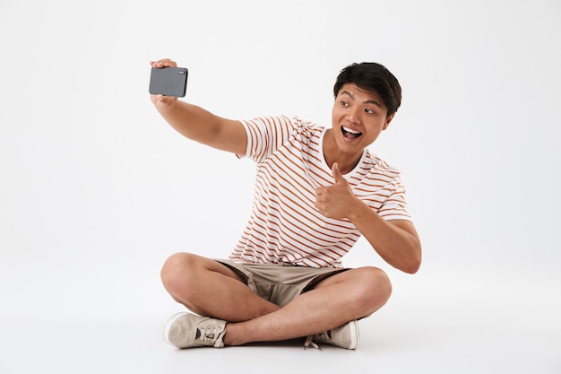 Retrato de un sonriente joven asiático tomando un selfie