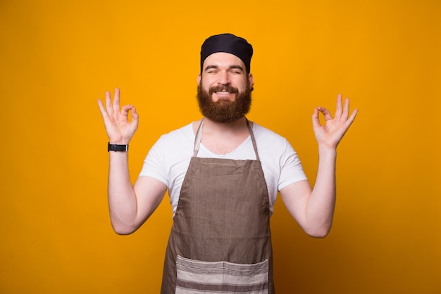 Retrato de sonriente joven chef hombre meditando sobre