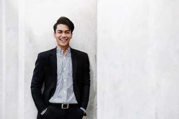 Retrato de sonriente joven empresario asiático en traje casual.