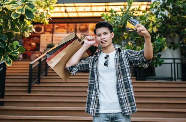 Retrato sonriente joven guapo en gafas de sol con bolsa de papel