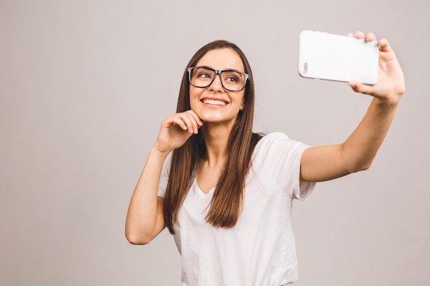 Retrato de una sonriente joven linda mujer haciendo foto selfie en smartphone