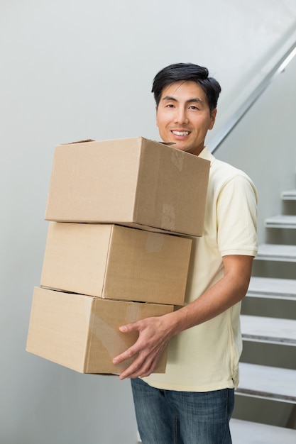 Retrato de un sonriente joven llevando cajas