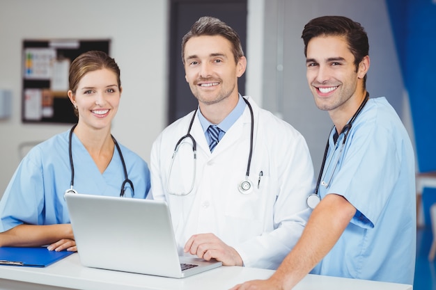 Retrato de sonriente médico y colegas con laptop