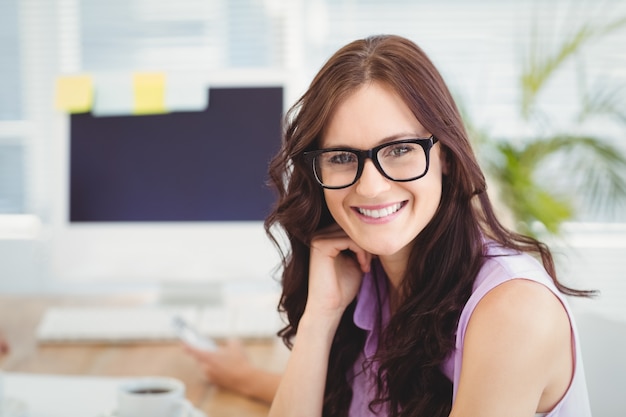 Retrato de sonriente mujer con anteojos en escritorio