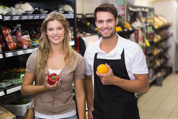 Retrato de sonriente mujer bonita rubia comprando un vegetal en el vendedor