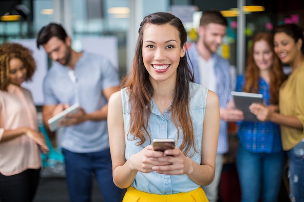 Retrato de sonriente mujer ejecutiva mediante teléfono móvil