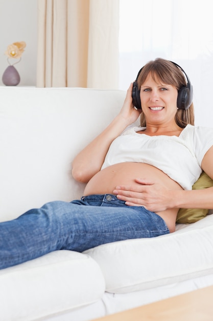 Retrato de una sonriente mujer embarazada escuchando música