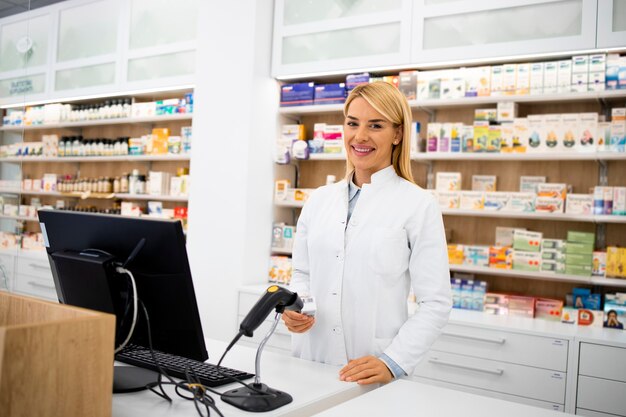 Retrato de sonriente mujer farmacéutica caucásica de pie en la farmacia y vendiendo medicamentos.