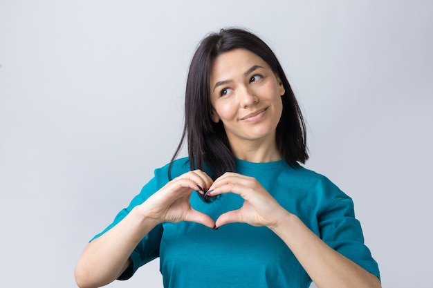 Retrato, de, un, sonriente, mujer joven, actuación, corazón, gesto, con, ella, dedos, aislado, encima, gris