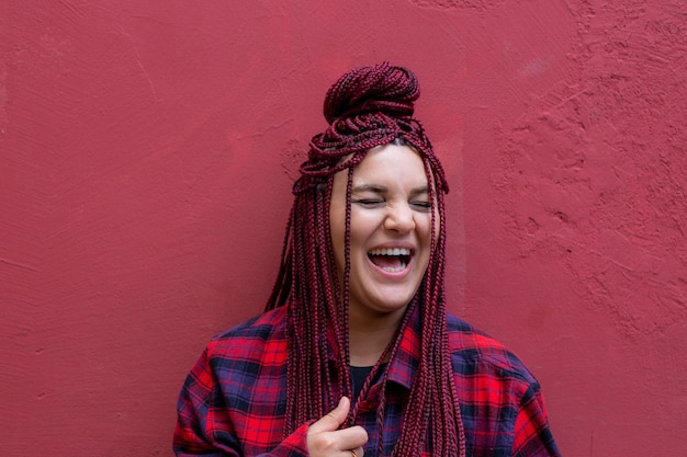 Retrato sonriente mujer joven con rastas rojas vistiendo una camisa a cuadros roja