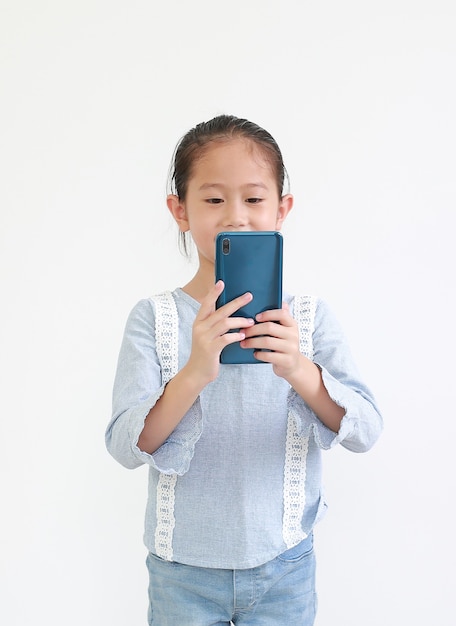 Retrato sonriente niña asiática niño con smartphone aislado en blanco