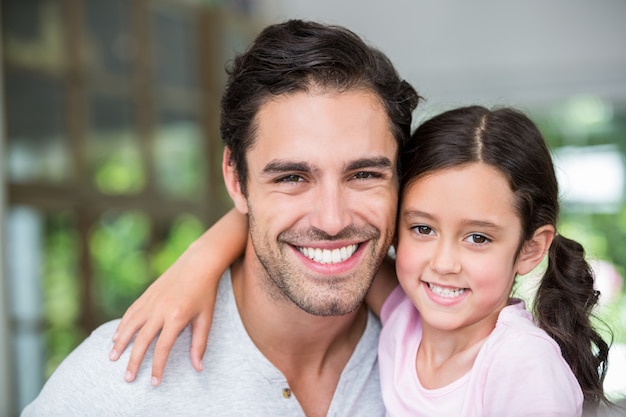 Retrato de sonriente padre e hija con brazo alrededor